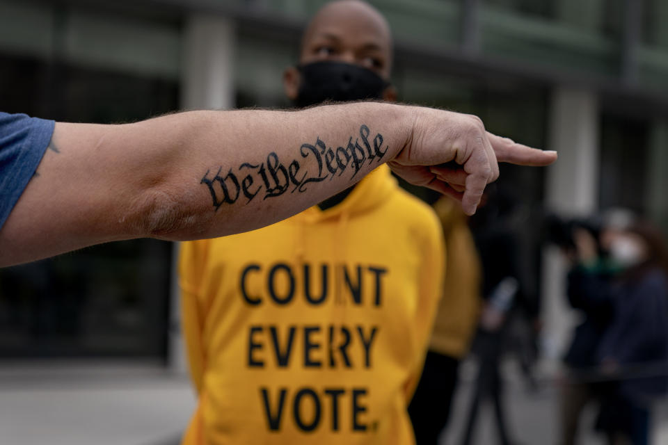 In this Nov. 5, 2020, file photo, the tattoo "We The People", a phrase from the United States Constitution, decorates the arm of Trump supporter Bob Lewis, left, as he argues with counter protestor Ralph Gaines while Trump supporters demonstrate against the election results outside the central counting board at the TCF Center in Detroit. President Donald Trump and his allies have fomented the idea of a “rigged election” for months, promoting falsehoods through various media and even lawsuits about fraudulent votes and dead voters casting ballots. While the details of these spurious allegations may fade over time, the scar it leaves on American democracy could take years to heal. (AP Photo/David Goldman, File)