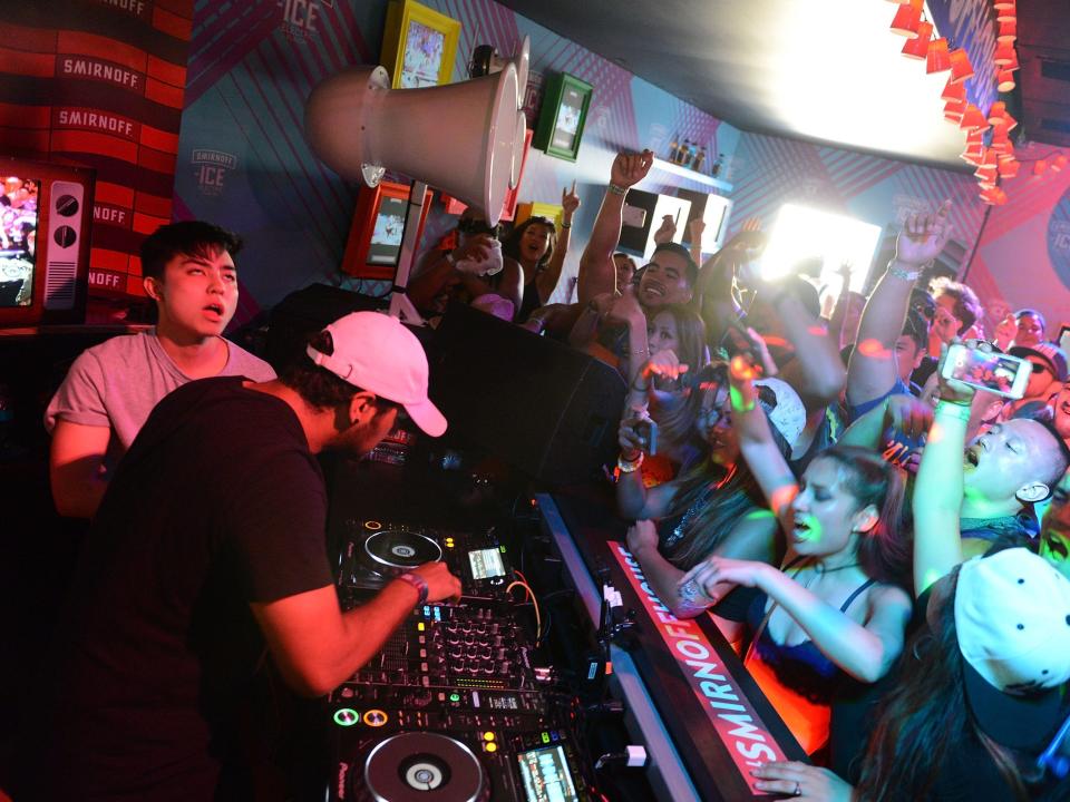 A stage with a DJ in front of a crowd of people.