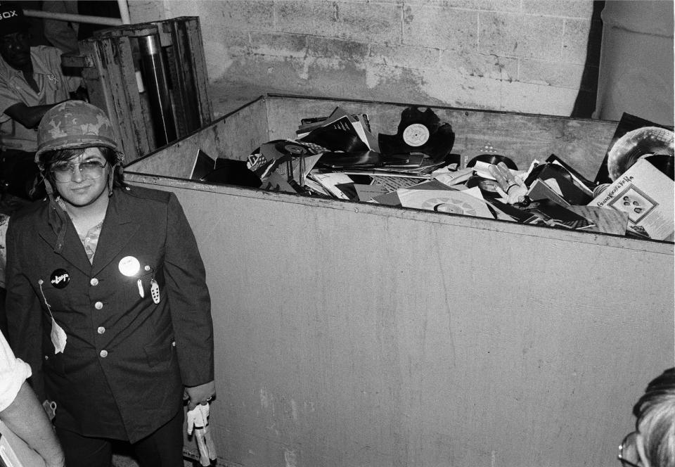 American disc jockey (from WLUP radio, 'The Loop') Steve Dahl stands beside of a crate full of unwanted disco records collected during an anti-disco promotion at Comiskey Park, Chicago, Illinois, July 12, 1979. The event, hosted by Dahl and held between games of a doubleheader between the Chicago White Sox and the Detroit Tigers, allowed fans to attend the games for 98 cents along with an unwanted record and, following the detonation of those records, eventually resulted in the White Sox forfeiture of the second game due to unsafe playing conditions when fans stormed the field causing serious damage to the venue and playing surface. (Photo: Paul Natkin/Getty Images)