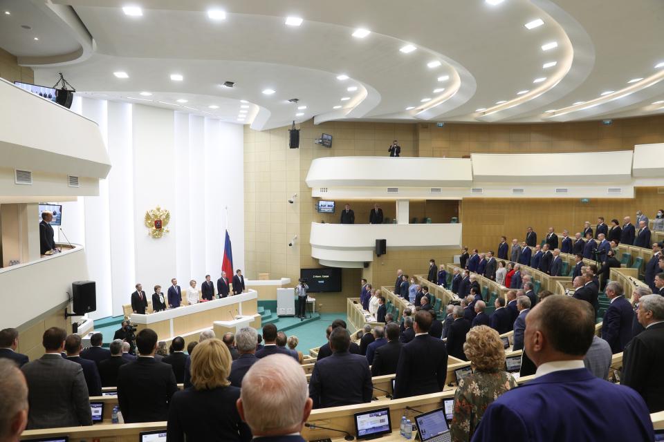 In this handout photo released by Federation Council of the Federal Assembly of the Russian Federation, Members of Federation Council of the Federal Assembly of the Russian Federation listen for the national anthem prior to their session in Moscow, Russia, Wednesday, June 2, 2021. The Russian parliament's upper house has voted to withdraw from an international treaty allowing surveillance flights over military facilities following the U.S. exit from the pact. (Federation Council of the Federal Assembly of the Russian Federation via AP)