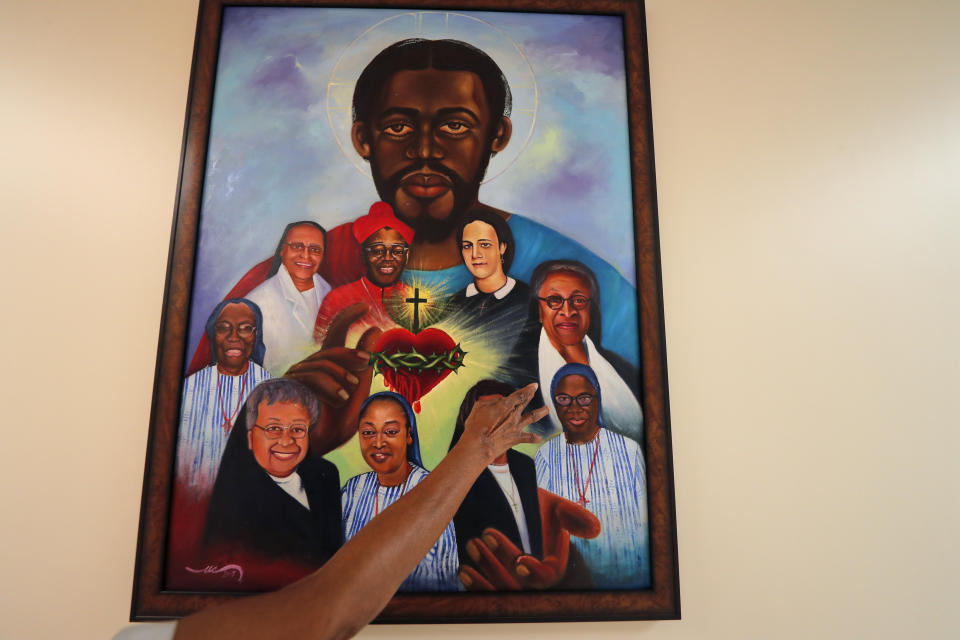 Sister Leona Bruner, a Mother Superior for the Sisters of the Holy Family, points out local religious figures in a painting that depicts a Black Jesus inside their Mother House in New Orleans, Thursday, July 23, 2020. The National Catholic Educational Association is forming an advisory committee to study how initiatives to place a new emphasis on teaching about racial justice, as well as the history of Black Catholics could be launched in the thousands of Catholic schools nationwide. (AP Photo/Gerald Herbert)