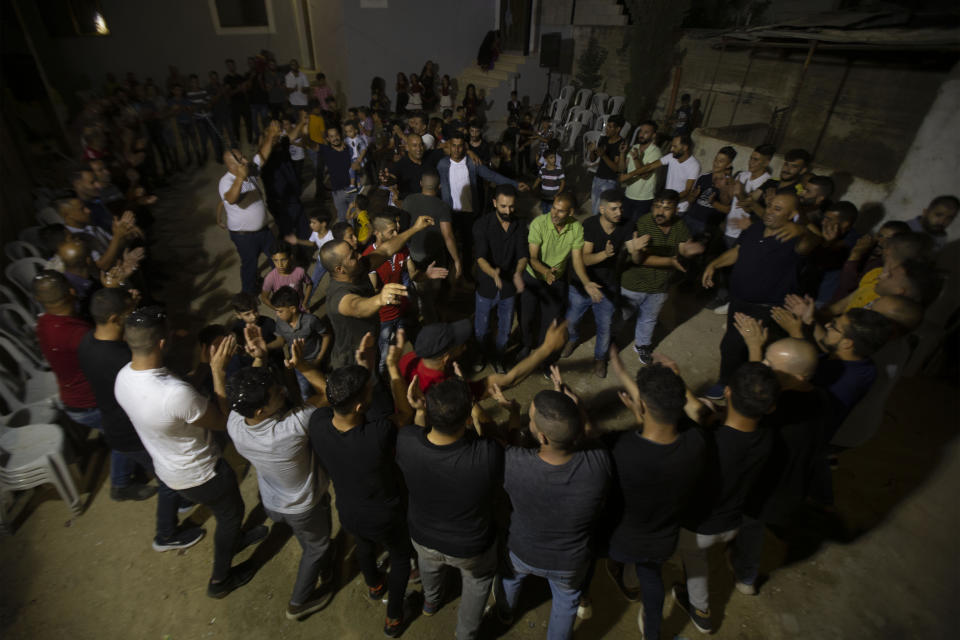 Palestinians celebrate during a wedding party in Azmut near the West Bank city of Nablus, Thursday, Sept. 24, 2020. In a region where marriage is the cornerstone of society, couples are plowing ahead with weddings, despite the deadly risks. From the Palestinian territories to the United Arab Emirates, officials attribute a spike in coronavirus cases to traditional, large-scale weddings that flout public health restrictions.(AP Photo/Majdi Mohammed)