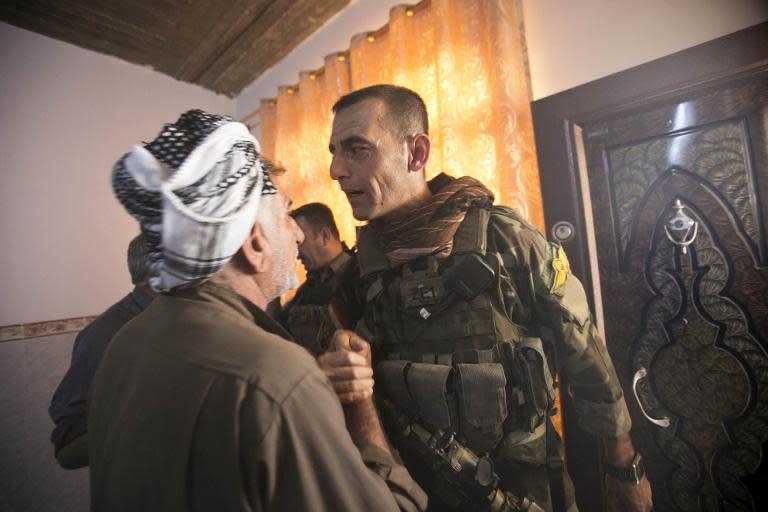 A member of Kurdish Peshmerga forces (R) talks to a leader of a local Shiite community on June 21, 2014