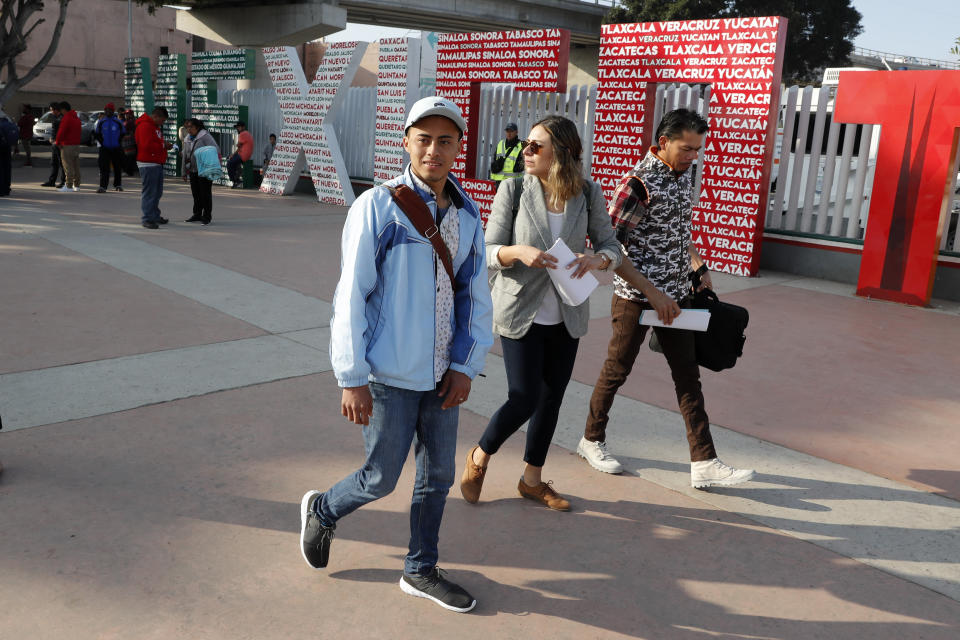 Dos hondureños caminan con su abogada mientras cruzan a Estados Unidos para comenzar sus casos de asilo, el martes 19 de marzo de 2019 en Tijuana, México. (AP Foto/Gregory Bull)