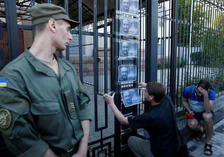 A man hangs a picture of Russian dissident journalist Arkady Babchenko, who was shot dead in the Ukrainian capital on May 29, on a fence of the Russian embassy in Kiev, Ukraine May 30, 2018. REUTERS/Gleb Garanich