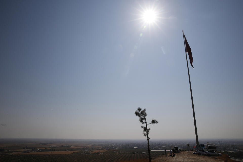 A Turkish flag on a hilltop at the Turkey-Syria border in the town of Ceylanpinar, Sanliurfa province, southeastern Turkey, Wednesday, Oct. 23, 2019, overlooking the town of Ras al-Ayn, Syria. Russian media reports say Russian military police have started patrols in northern Syria as a Turkish-Russian agreement giving Syrian Kurdish fighters 150 hours to withdraw from almost the entire northeast border region of Syria came into effect. (AP Photo/Lefteris Pitarakis)