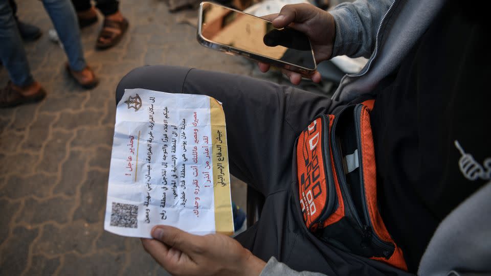 A Palestinian holds a leaflet dropped by Israeli forces, urging residents to leave Al-Qarara, Khuza'a, Bani Suheila and Maan regions of the city of Khan Younis, in Gaza on Saturday. - Abed Zagout/Anadolu/Getty Images