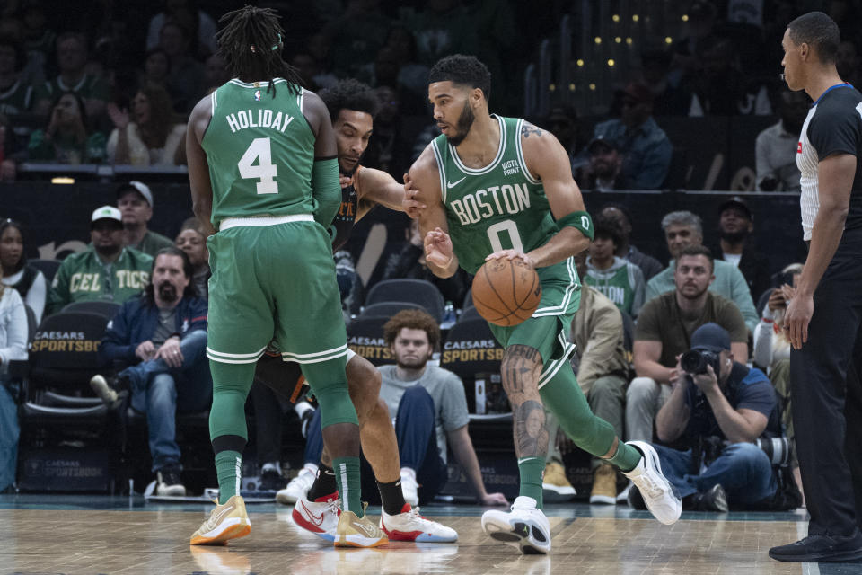 Boston Celtics guard Jrue Holiday (4) provides a screen for teammate forward Jayson Tatum (0) who drives during the first half of an NBA basketball game against the Washington Wizards in Washington, Sunday, March 17, 2024. (AP Photo/Manuel Balce Ceneta)