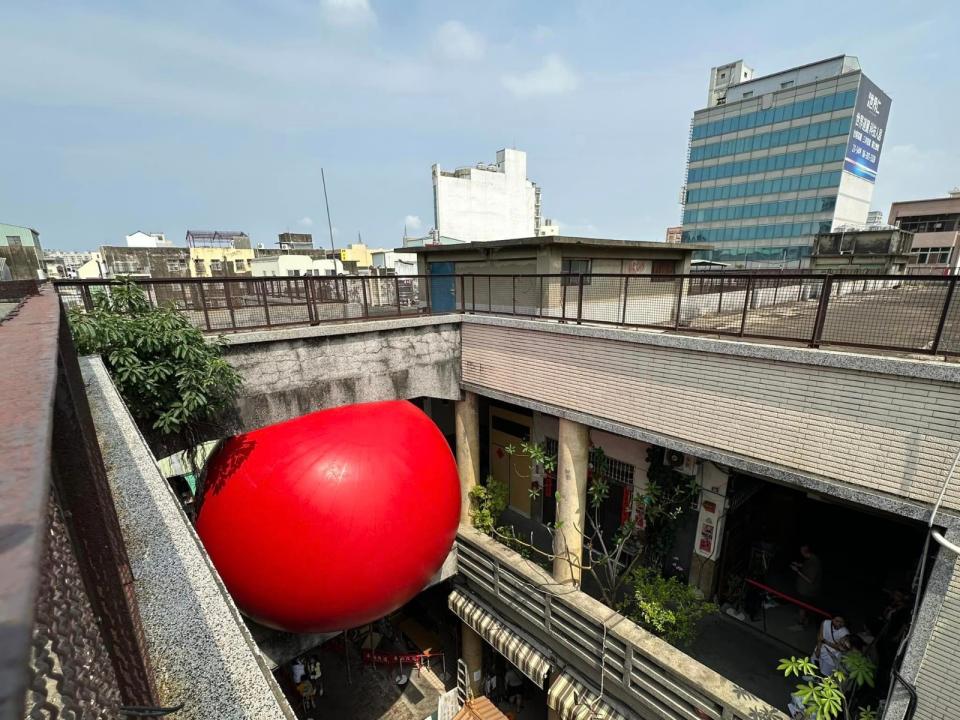 美國藝術家波希克（Kurt Perschke）發起「紅球計畫」，30日移至中西區永樂市場，置放在兩棟建築相通的人行天橋上。翻攝自台南式 Tainan Style臉書粉專
