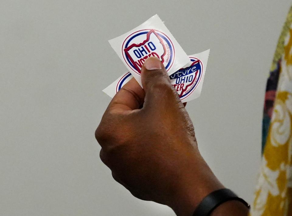 An early voter holds a sticker at the Board of Elections in Norwood.