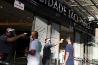 Foto del jueves de un grupo de personas a las que le toman la temperatura antes de entrar al shopping Cidade Sao Paulo en medio de la pandemia de coronavirus