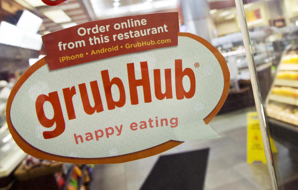 FILE - In this April 4, 2014 file photo, a sign for GrubHub is displayed on the door to a New York restaurant.  The owner of KFC and Taco Bell, is teaming up with Grubhub to expand its delivery business. Yum Brands said Thursday, Feb. 8, 2018,  that Grubhub will run KFC and Taco Bell delivery and online ordering in the United States. GrubHub will provide delivery people and its technology.(AP Photo/Mark Lennihan, File)