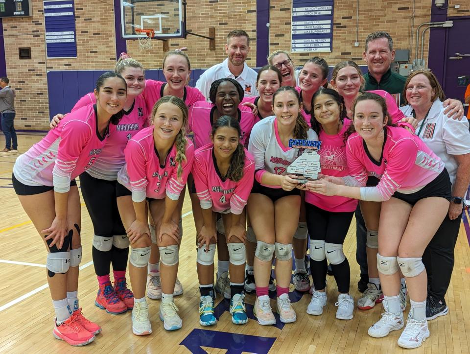 Mandarin players and coaches celebrate with the trophy after defeating Fletcher in the Gateway Conference high school volleyball championship.