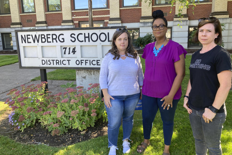 From left, Beth Woolsey, Tai Haden-Moore and AJ Schwanz , who are members of a group called Newberg Equity in Education which is advocating for inclusion and equity in schools, stand in front of a school district office in Newberg, Ore., on Tuesday, Sept. 21, 2021. The Newberg School Board has banned educators from displaying Black Lives Matter and gay pride symbols, prompting a torrent of recriminations and threats to boycott the town and its businesses. (AP Photo/Andrew Selsky)