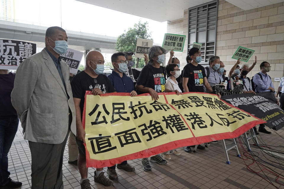 Hong Kong businessman and media tycoon Jimmy Lai, left, and other pro-democracy activists hold a banner after arriving at a court in Hong Kong, Friday, Sept. 18, 2020. Pro-democracy activists including Lai, former lawmakers Martin Lee and Lee Cheuk-yan were among of 15 pro-democracy activists appeared in court for charges of participating and organizing anti-government protests last year. The banner reads "Civil disobedience, fearless and invincible, facing autocracy, Hong Kong people rebellion." (AP Photo/Kin Cheung)