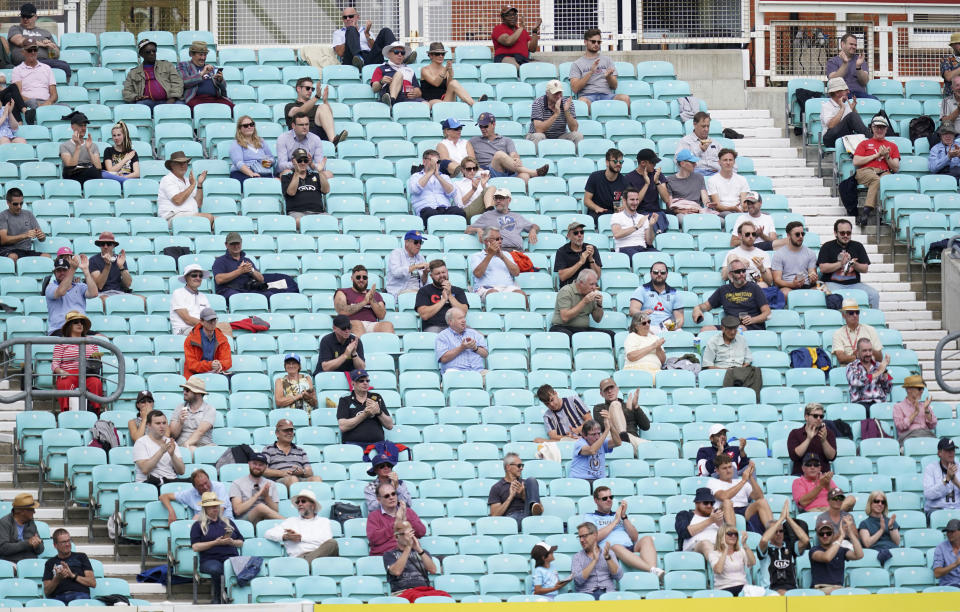 Spectators observe social distancing in the stands during the friendly cricket match at the Oval, London, Sunday, July 26, 2020. Spectators have been allowed into a sporting event in England for the first time since March when coronavirus prevention measures were tested at a cricket match between Surrey and Middlesex at The Oval ahead of a planned wider reopening of stadiums in October. Alternate rows were used across two stands and advisory signs were on show for the friendly match being watched by 1,000 people. (John Walton/PA via AP)