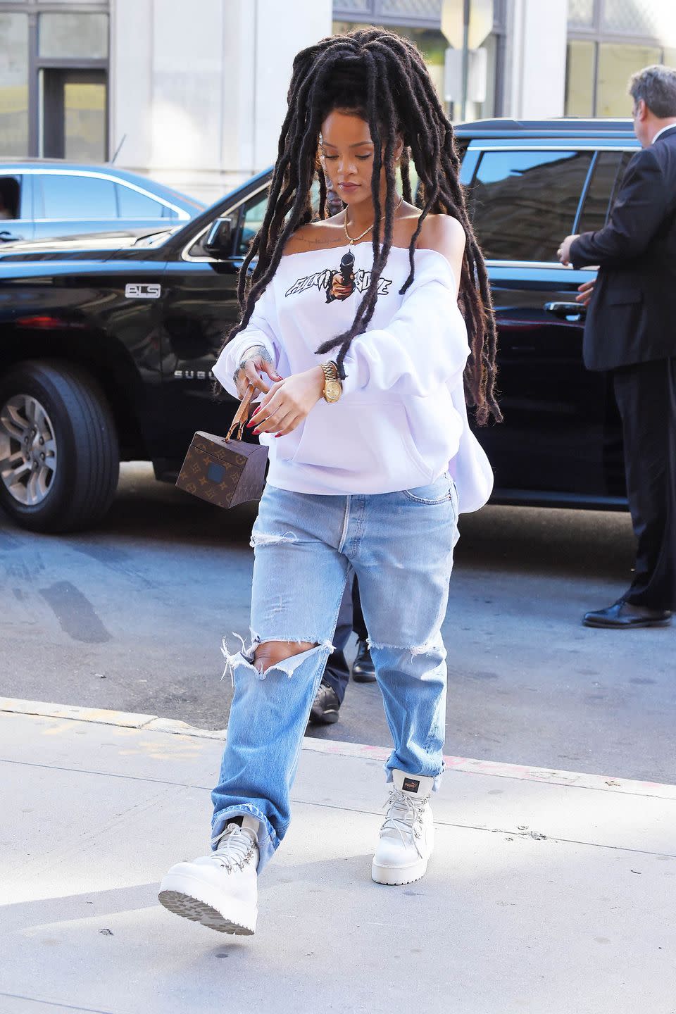 <p>In an off-the-shoulder white sweatshirt, ripped baggy jeans, white platform Puma boots Louis Vuitton bag and gold watch while out in New York City. </p>