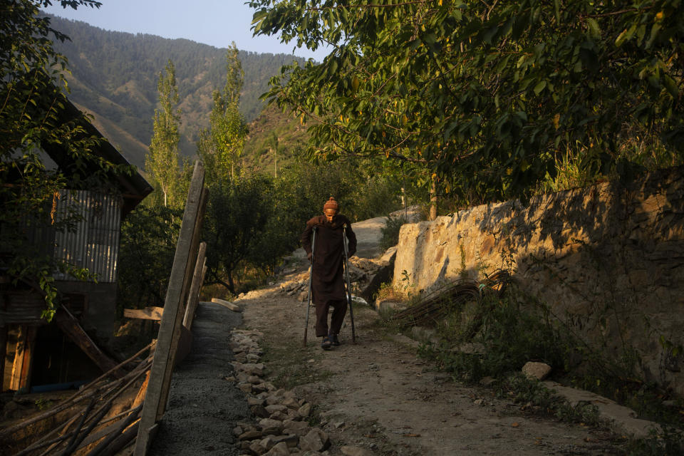 Mohammad Yaqoob who survived a wild bear attack moves towards his home at Dardkhor village in Srinagar, Indian controlled Kashmir, Monday, Aug. 24, 2020. "I was with cattle near my house, suddenly a bear came from the forest side and jumped on me. I was having a dog along with me that time which saved me. Unfortunately my right leg was damaged leaving me handicapped for lifetime.", Yaqoob said. (AP Photo/Mukhtar Khan)