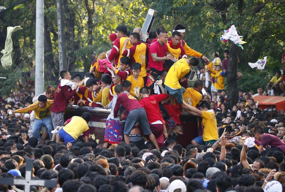 Filipino Roman Catholic devotees climb the carriage to kiss and rub with their towels the image of the Black Nazarene to celebrate its feast day Monday, Jan. 9, 2017 in Manila, Philippines. The raucous celebration drew tens of thousands of devotees in a barefoot procession for several hours around Manila streets and end up with several people injured. (AP Photo/Bullit Marquez)