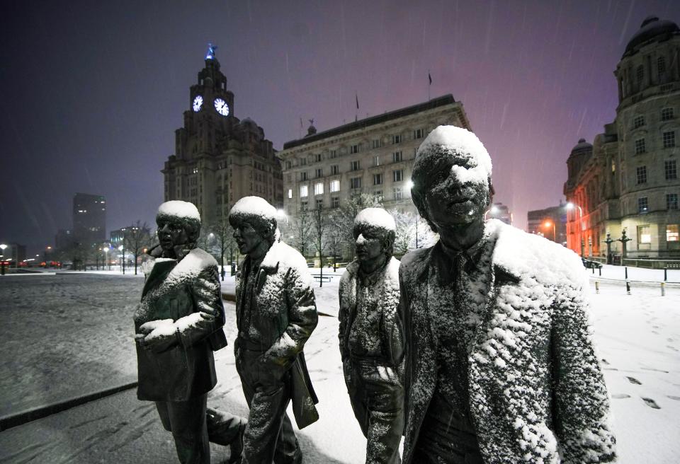 Snow falls on the Beatles Statue at Pier Head, Liverpool. Much of Britain is facing another day of cold temperatures and travel disruption after overnight lows dropped below freezing for the bulk of the country. A 