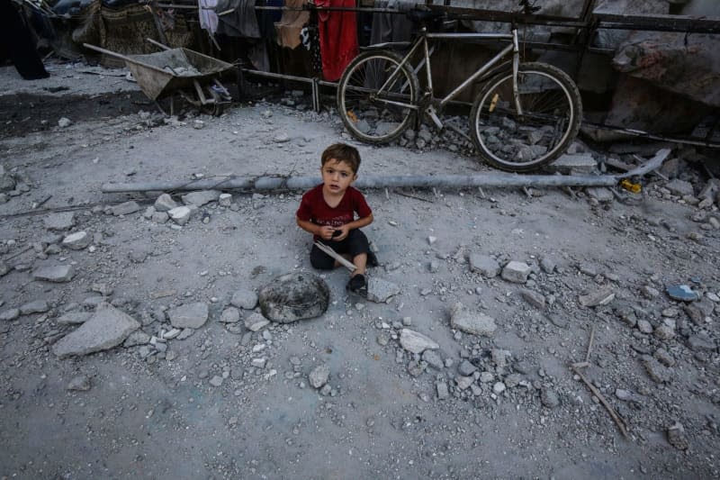 A Palestinian child is among the damage after an Israeli airstrike on a school for displaced persons of the United Nations Relief and Works Agency for Palestine Refugees in the Near East (UNRWA) in the Nuseirat refugee camp, in the middle of the Gaza Strip.  Omar Naaman/dpa