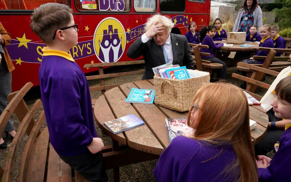  Boris Johnson joins a Year 4 reading lesson outside during a visit  - Getty