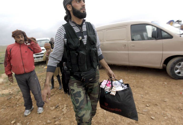 A rebel fighter helps Syrian refugees cross the border from Syria into Jordan, near Mafraq, on February 18, 2013. The United Nations says more than four million people inside Syria are in desperate need of aid, up sharply from 2.5 million in September