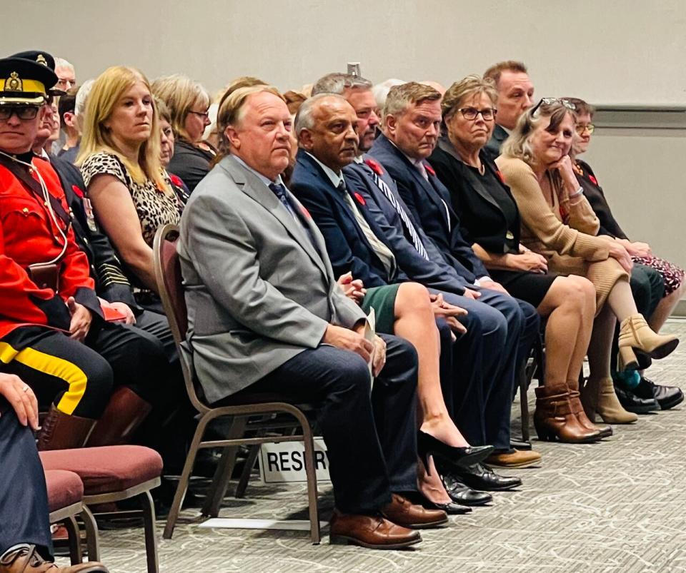 Kamloops Mayor Reid Hamer-Jackson, left side in a grey suit, sits next to several city councillors during their swearing-in ceremony in November 2022.