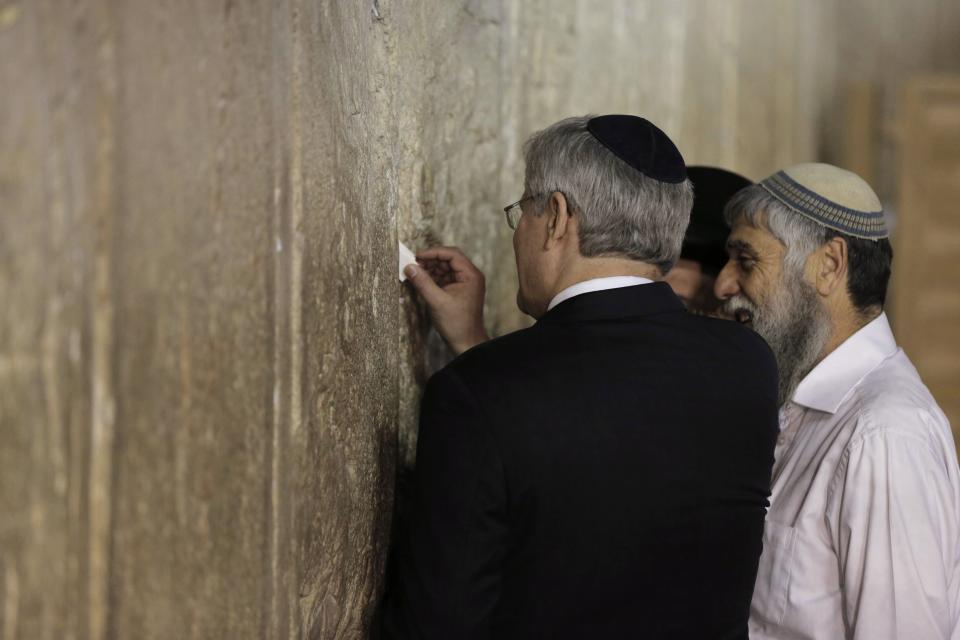 Canada's Prime Minister Stephen Harper (L) places a note in between the stones of the Western Wall, Judaism's holiest prayer site, during a visit to Jerusalem's Old City January 21, 2014. Harper told Israel's parliament on Monday any comparison between the Jewish state and apartheid South Africa was "sickening", drawing a standing ovation - and an angry walkout by two Arab legislators. REUTERS/Ammar Awad (JERUSALEM - Tags: POLITICS)