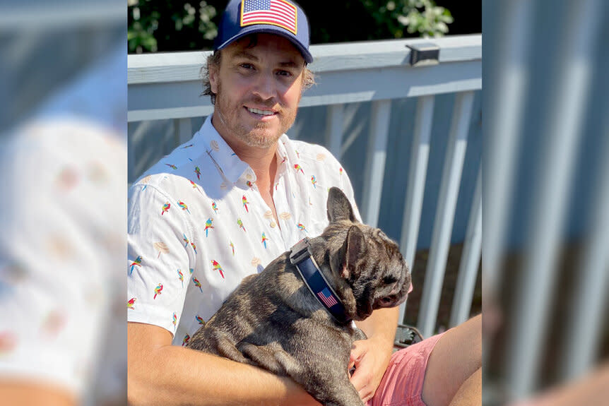 Shep Rose sitting on a deck while carrying his dot, Lil Craig.