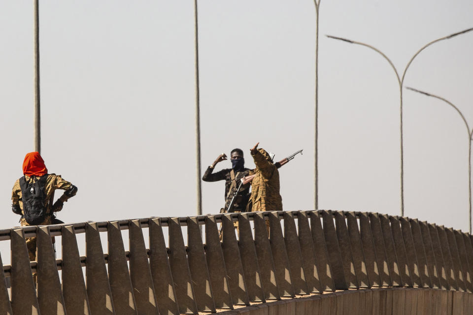 Mutinous soldier stand on a bridge at the Bobo interchange near the Lamizana camp in Burkina Faso's capital Ouagadougou Sunday Jan. 23, 2022. Witnesses are reporting heavy gunfire at a military base raising fears that a coup attempt is underway. Government spokesman Alkassoum Maiga acknowledged the gunfire but denied that the military had taken over the West African country. (AP Photo/Sophie Garcia)