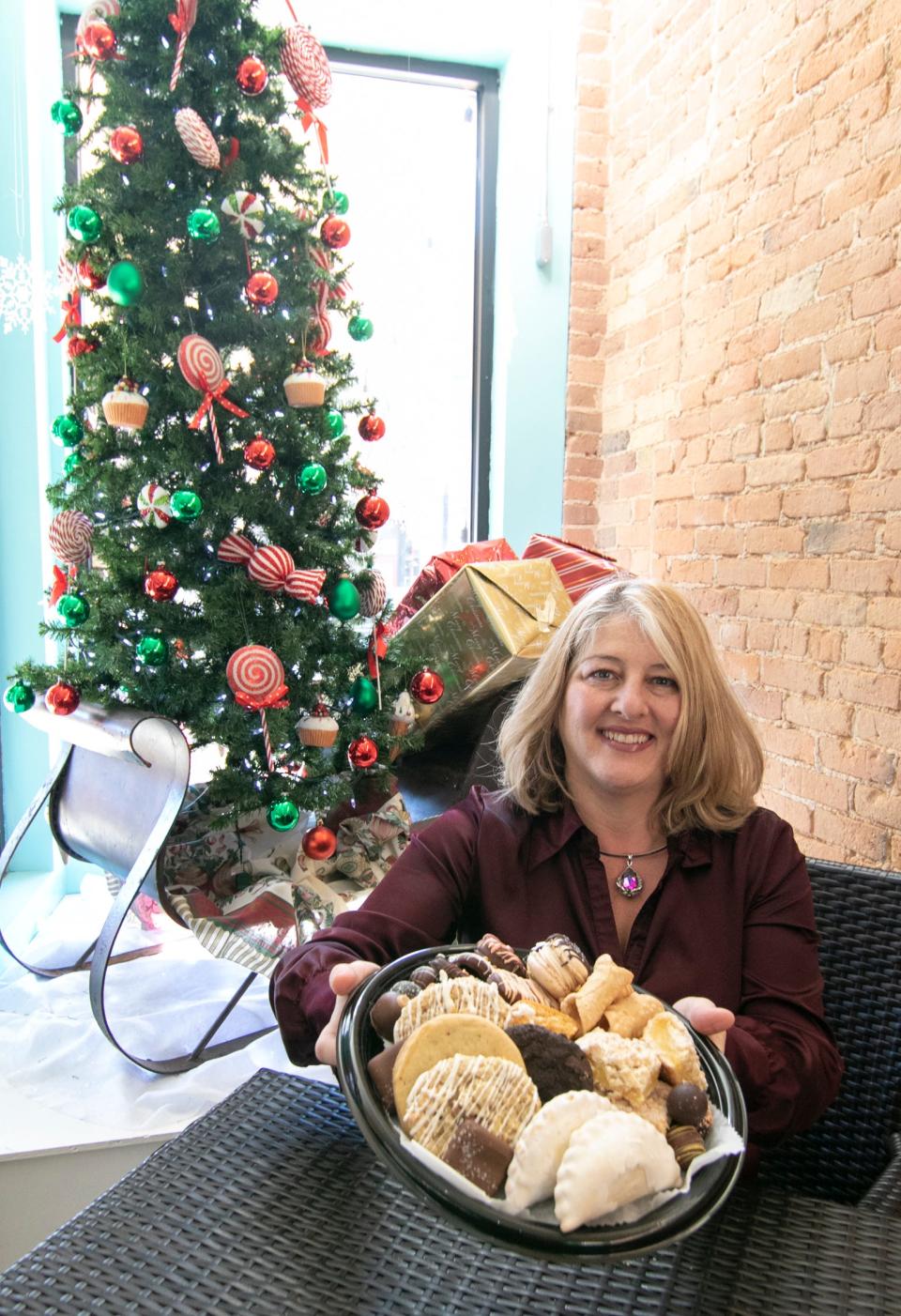 Teresa Chalifour, owner of The Chocolate Boutique and Bakery, holds a sweet tray sampling in her downtown Howell store Tuesday, Nov. 23, 2021. On the tray are hand pies, cookies, truffles, lemon bars, pumpkin roll slices, mini cannoli, French macarons and assorted chocolates.