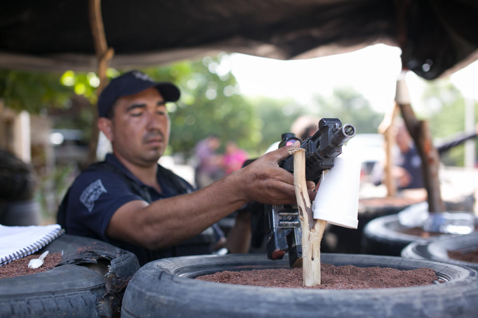 Mexican police places his weapon on a barricade at check point in Tepalcatepec, Michoacan state, Mexico Saturday, Aug. 31, 2019. Heavily armed bands clashed Friday in Tepalcatepec, leaving at least 9 dead, according to authorities. (AP Photo/Armando Solis)