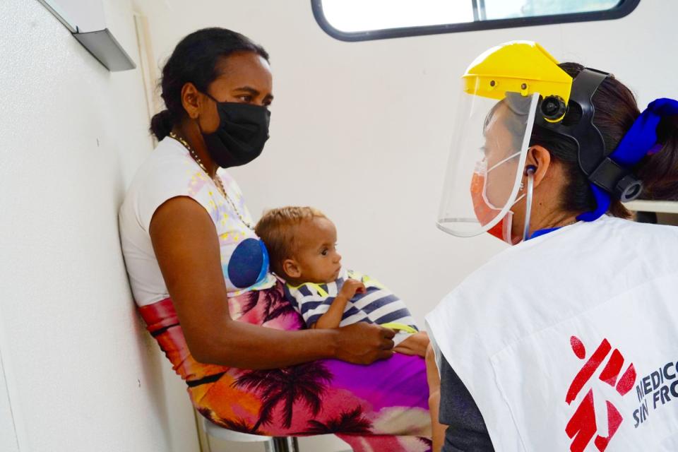 A woman holds a child while talking to another woman