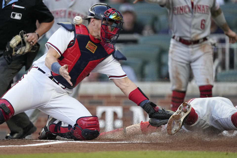 Cincinnati Reds' Jake Fraley (27) slides past Atlanta Braves catcher Sean Murphy (12) to score on a two-run single by Tyler Stephenson during the first inning of a baseball game Wednesday, April 12, 2023, in Atlanta. (AP Photo/John Bazemore)