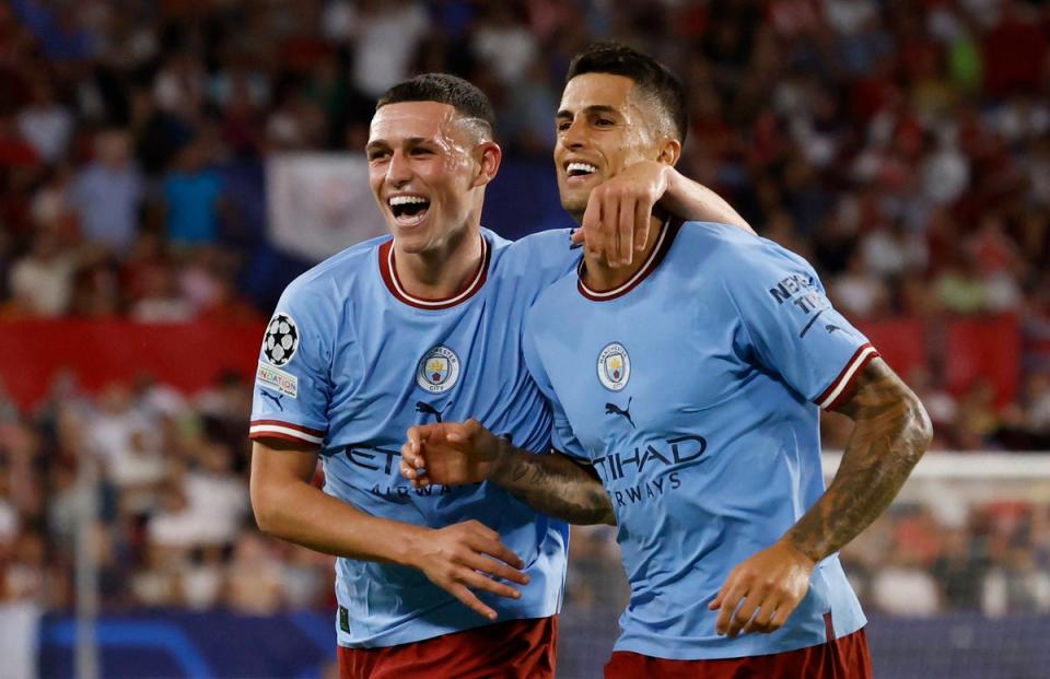 Phil Foden celebrates scoring Manchester City’s second goal agains Seville with Joao Cancelo (Reuters)