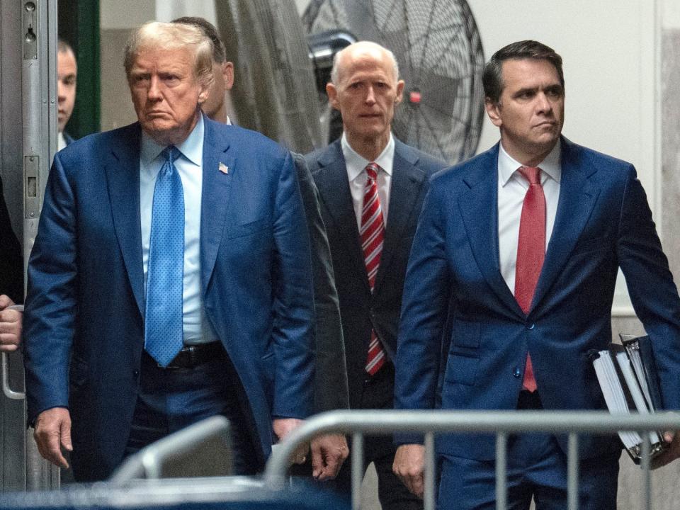 Florida Sen. Rick Scott walks behind Trump at the trial on May 9.