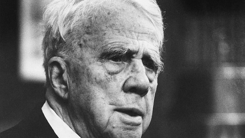 robert frost folding his hands in front of his chest as he looks off camera to the right