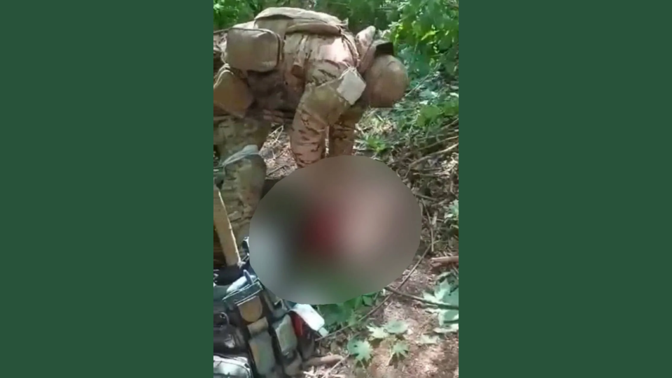 A serviceman wearing a white taped band, which Russian soldiers use as an identifying symbol, is seen torturing and killing a man, allegedly a Ukrainian prisoner of war. (Screenshot from the video)