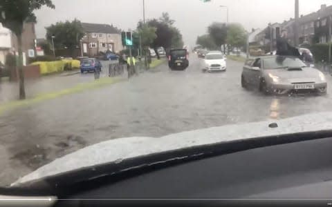 Man on a car roof not appearing to move through the flooded street in the Corstorphine area of Edinburgh