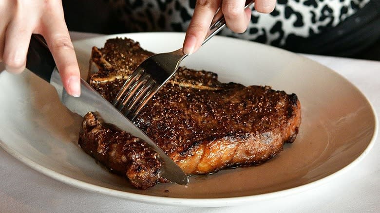 woman cutting steak on plate