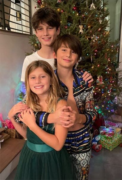 Three children stood in front of a Christmas tree