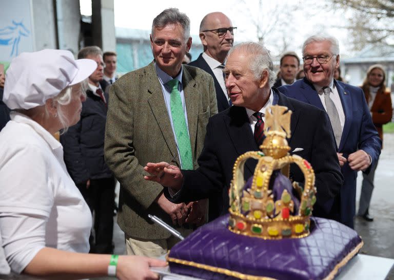 Carlos III saluda a una empleada al recibir una torta en forma de corona durante su visita a Berlín