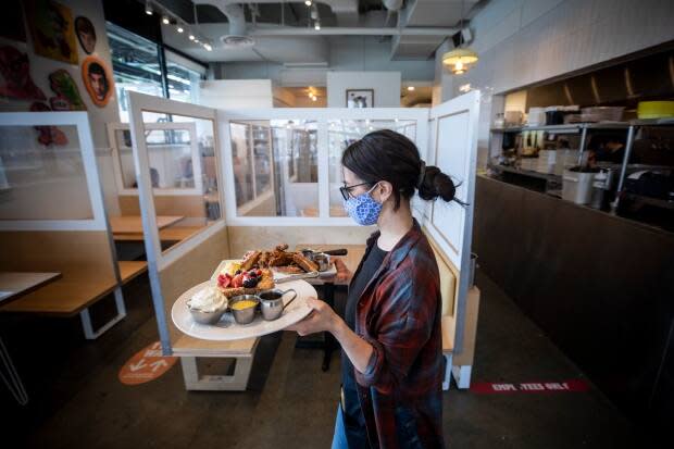 A server is pictured bringing food to indoor diners at Yolks restaurant in Vancouver after the province entered Step 1 of its reopening plan on May 25. B.C. moved into Step 2 on Tuesday. (Ben Nelms/CBC - image credit)