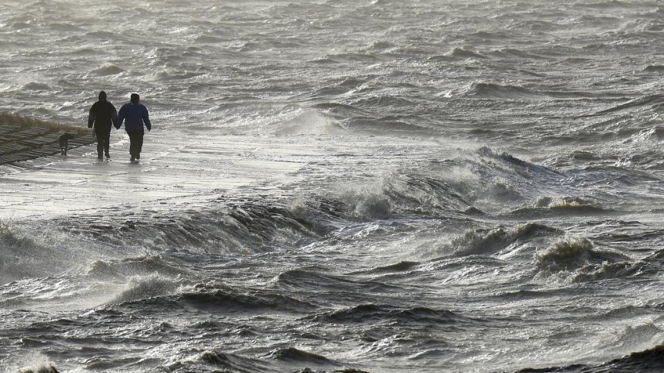 Passanten trotzen am Nordseedeich dem Sturm.