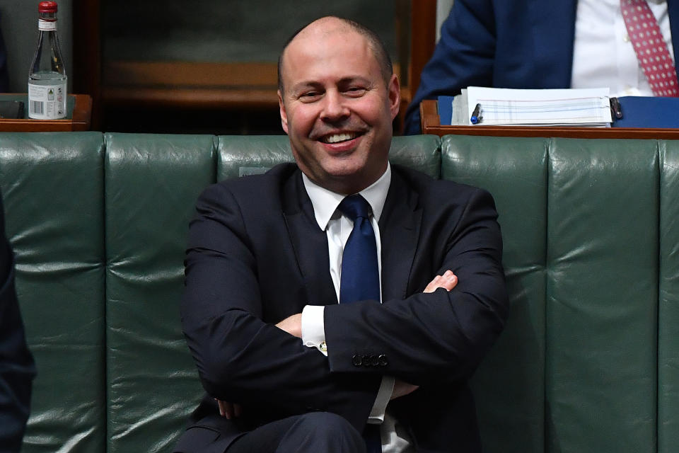 Treasurer Josh Frydenberg smiles while sitting in Parliament.