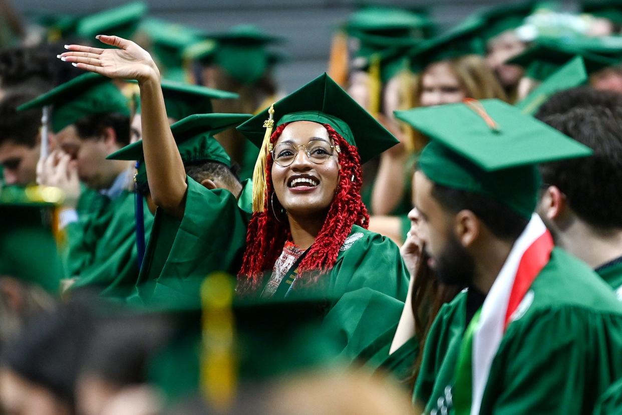 Psychology graduate Valencia Martin waves to people in the crowd during the Michigan State University spring convocation on Friday, May 6, 2022, at the Breslin Center in East Lansing.