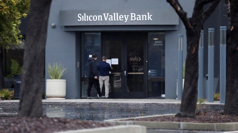 Bir adam California, Santa Clara'daki Silicon Valley Bank'ın kapısına bir tabela asıyor.