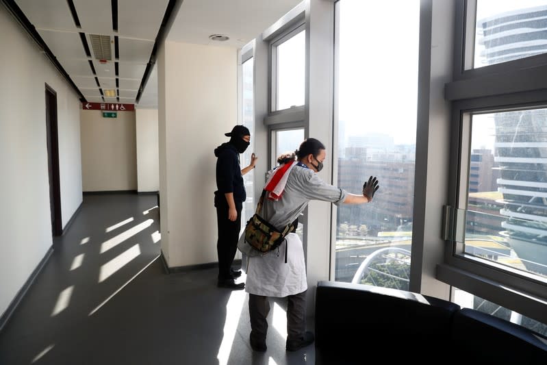 Protesters look out of windows for police positions as they search for fellow protesters who might be hiding, at the Hong Kong Polytechnic University (PolyU)