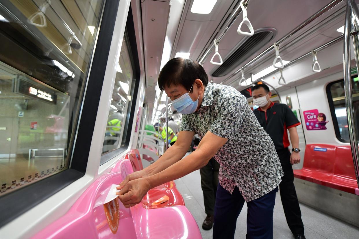 Transport Minister Khaw Boon Wan removing a safe distancing sticker from the seat of an MRT train. (PHOTO: Facebook / Khaw Boon Wan)